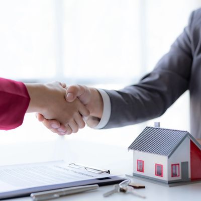 Real estate agent shakes hands with a client to sign a home purchase contract