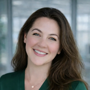Smiling woman with long brown hair wearing a green top and necklace.