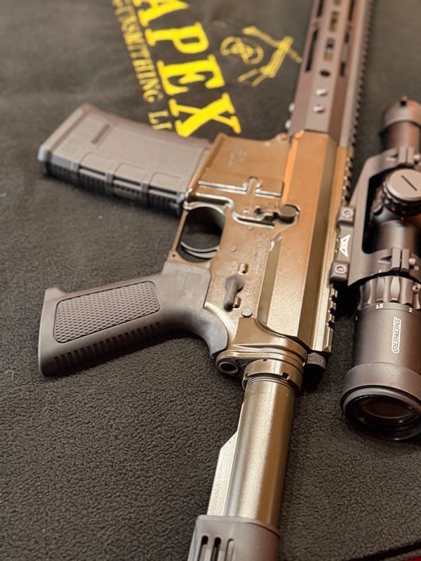 Close-up of a rifle with a scope on a black surface.