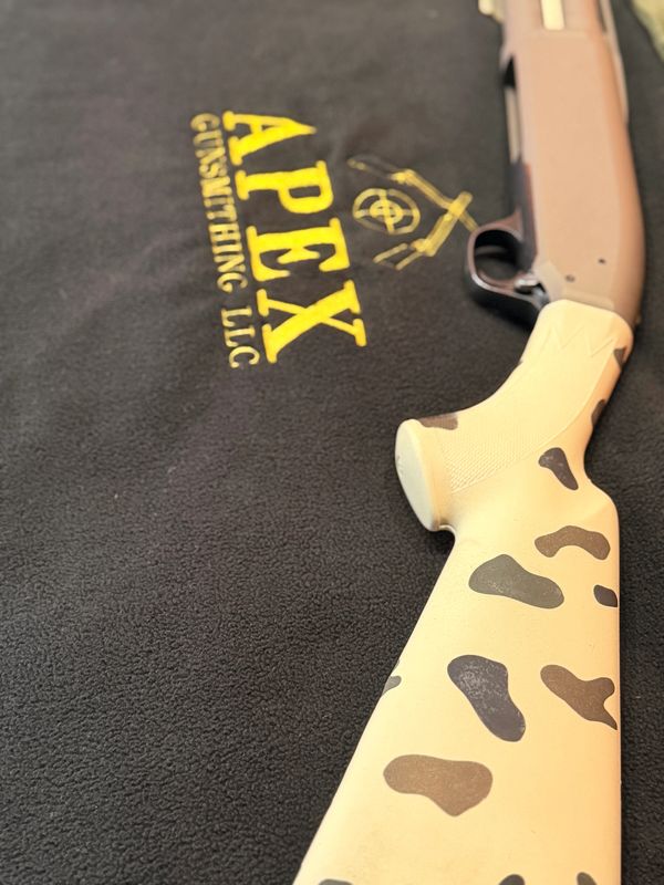 Shotgun with camo-patterned stock on Apex Gunsmithing cloth.