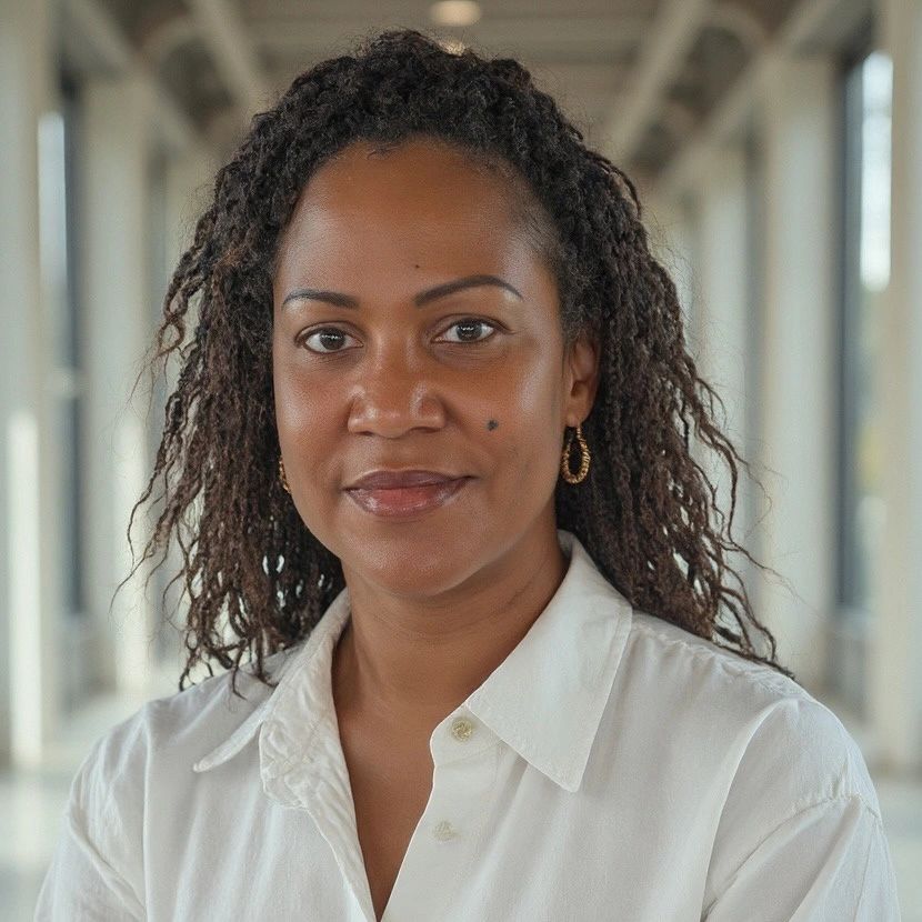 Confident woman with natural hair wearing a white shirt and gold hoop earrings.