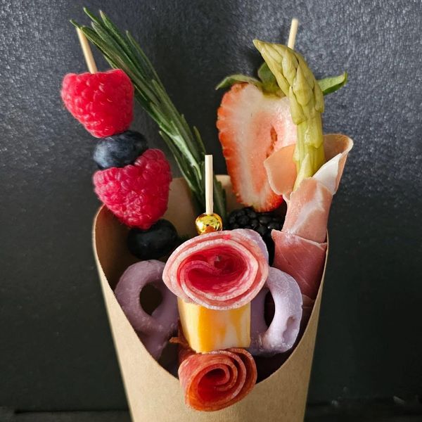 Fruit and charcuterie skewer arrangement in a cup.