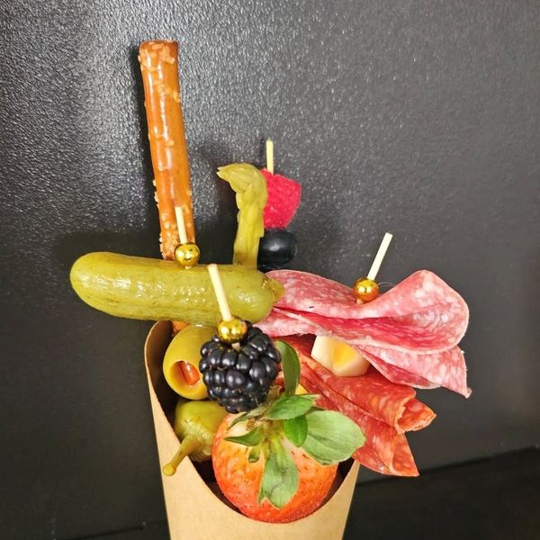 Charcuterie cone with meats, fruits, and snacks.
