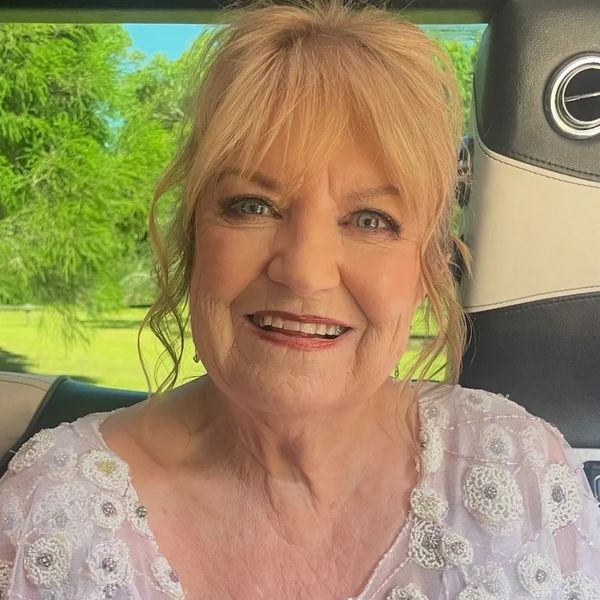 Smiling elderly woman holding a bouquet of flowers in a car.