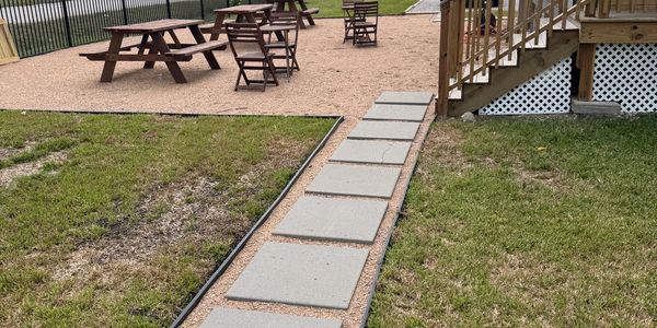 Concrete path leading to an outdoor seating area with picnic tables and chairs.