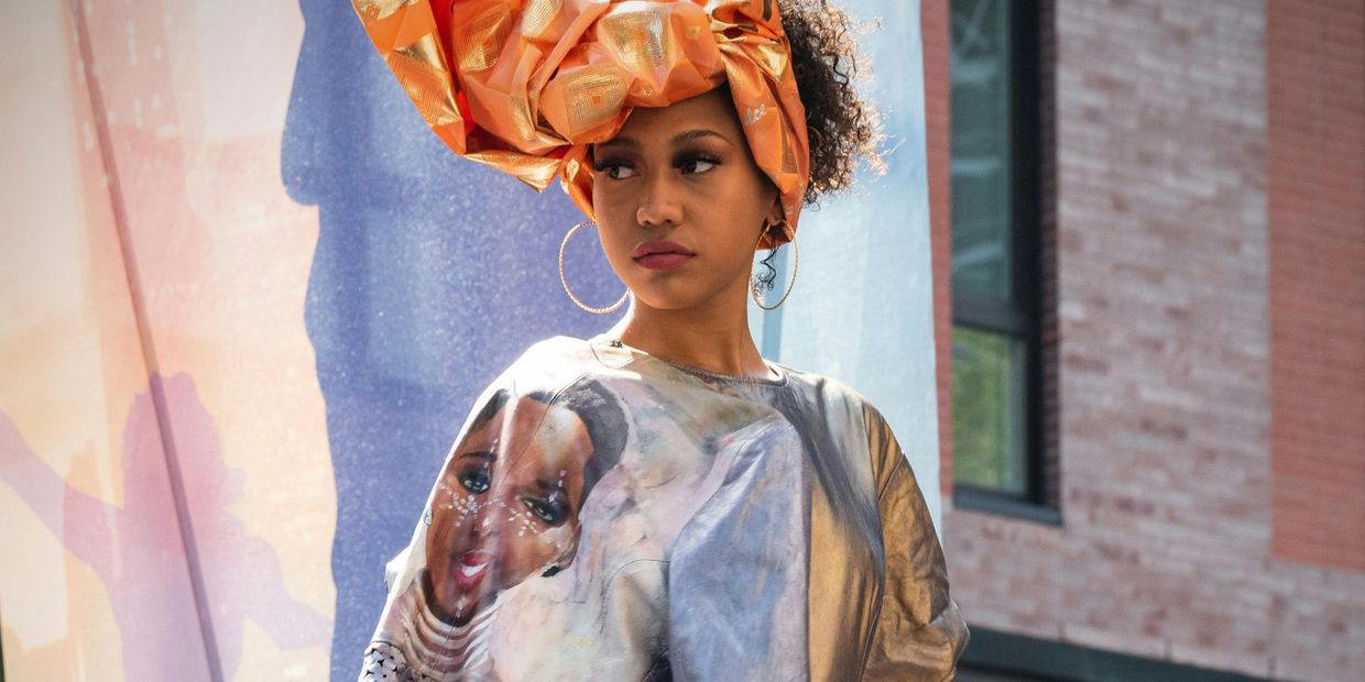 Woman in a metallic dress and vibrant orange headwrap posing outdoors.