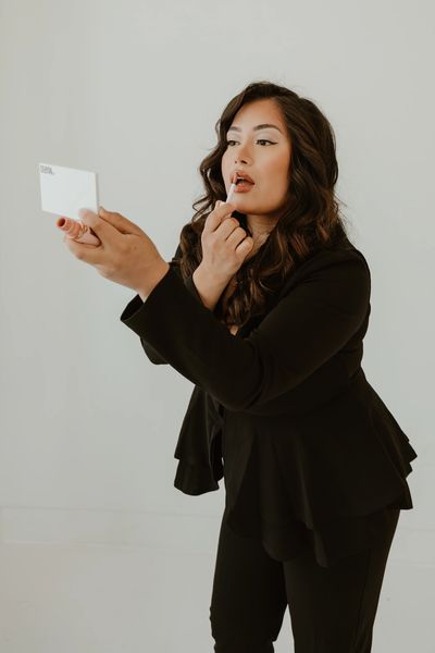 Woman applying lipstick using a mirror.