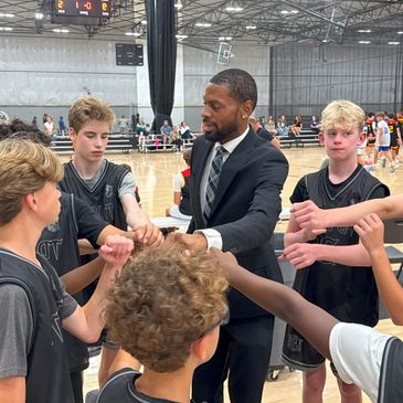 Coach motivating youth basketball team during game huddle.