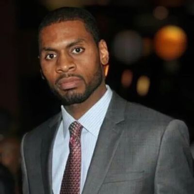 Man in a gray suit and tie looking seriously at the camera.