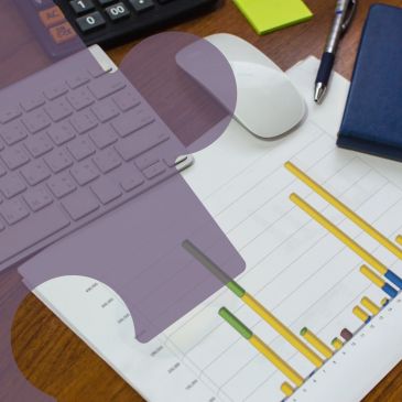 Workspace with keyboard, mouse, pen, notebook, and bar chart on paper.