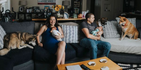 A family with newborns and dogs relaxing on a couch in their living room.