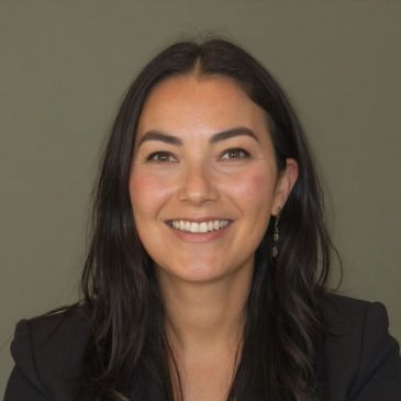 Young woman with dark hair smiling against a plain background.