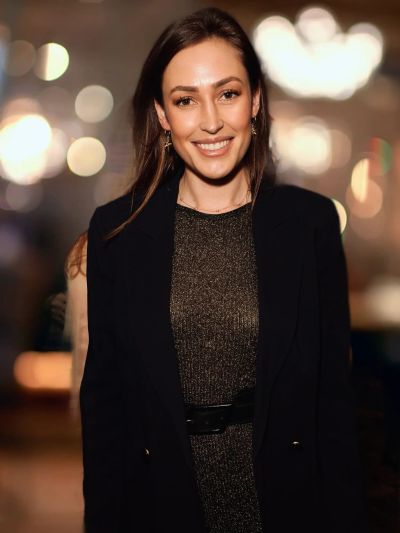 Smiling woman dressed in a black outfit with glowing background.