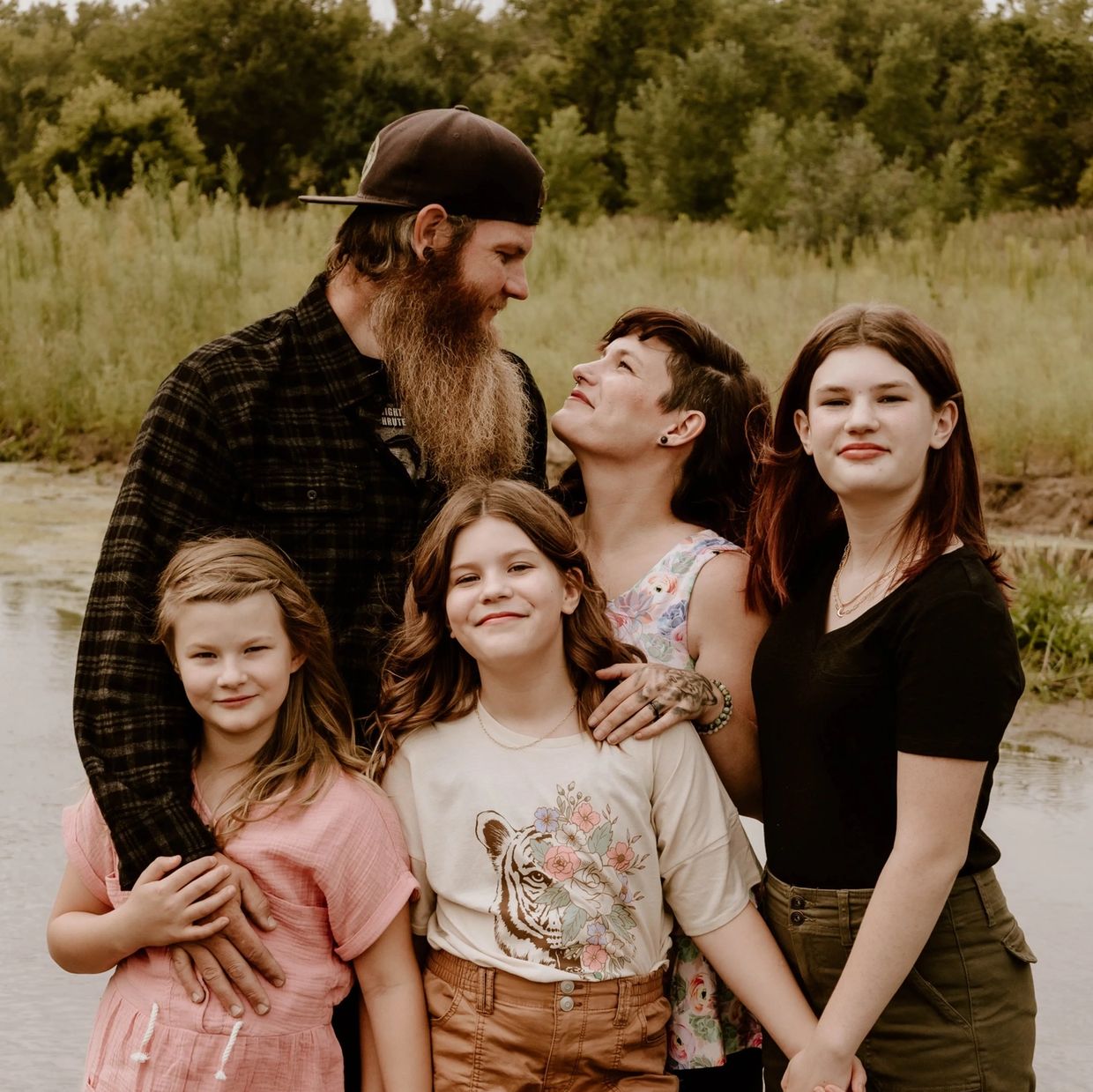 Christian mom with her husband and four daughters standing in water, smiling and embracing. A family-centered lifestyle and digital marketing blogger building a faith-based business from home.