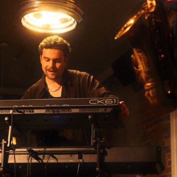 Man playing a keyboard under warm light.