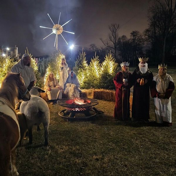 A nighttime nativity scene with people dressed as biblical characters and animals.