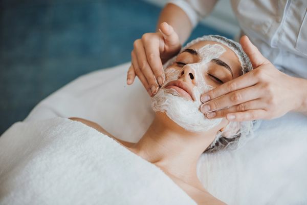 person relaxes on a spa table, receiving a facial treatment with creamy mask applied and environment