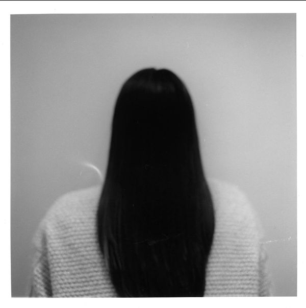 Person with long hair facing away, wearing a textured sweater.