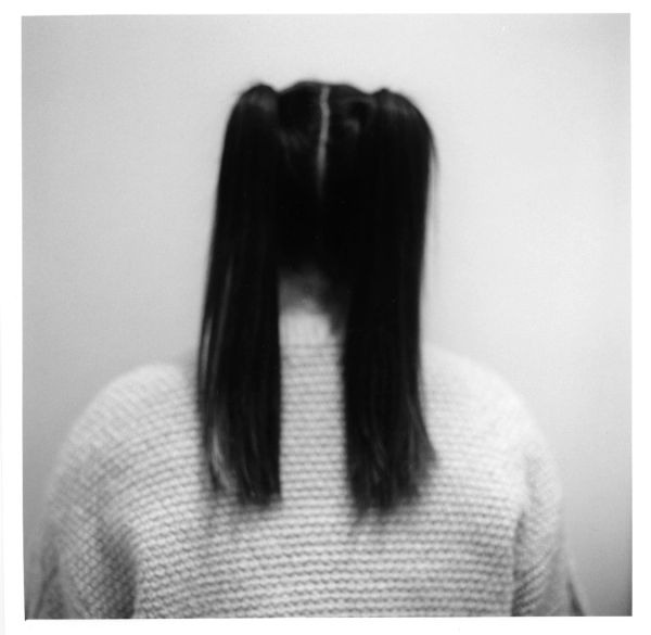 Back view of a person with two ponytails and a knitted sweater.