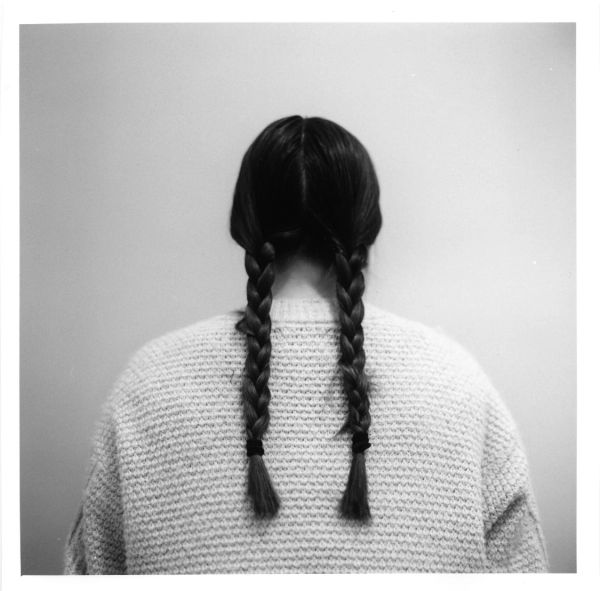 Back view of a person with two braided pigtails wearing a textured sweater.