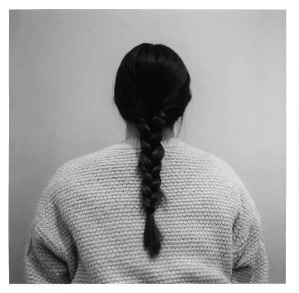 Person with a braid wearing a textured sweater, viewed from behind.