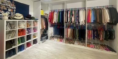 Organized walk-in closet with shelves, hanging clothes, and shoes.