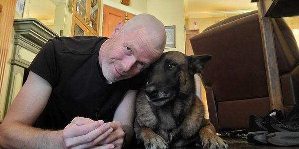 Man and dog lying close together on the floor indoors.