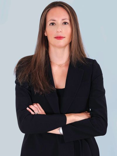 Femme professionnelle avec veste noire, bras croisés.