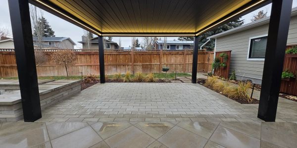 Modern black pergola with integrated lighting in a backyard patio.