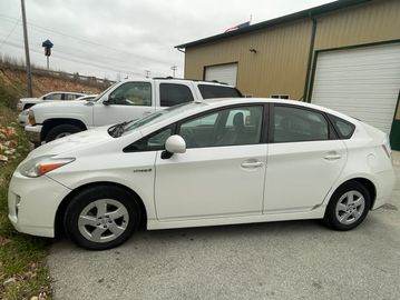 White Toyota Prius parked beside a building on a cloudy day.