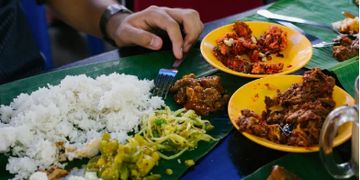 A traditional meal served on a banana leaf with rice and various side dishes.