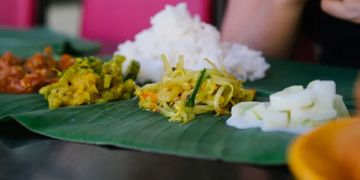 Traditional Indian meal served on a banana leaf with rice and vegetable sides.