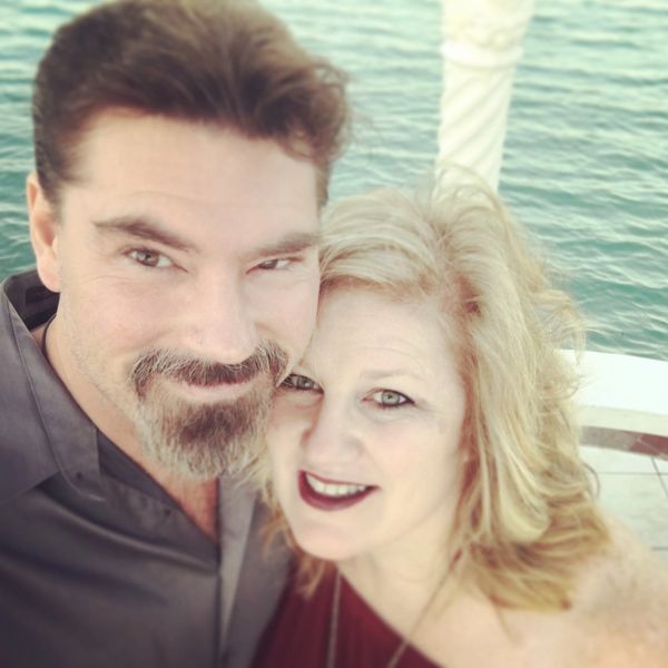 A happy couple taking a selfie near the water.