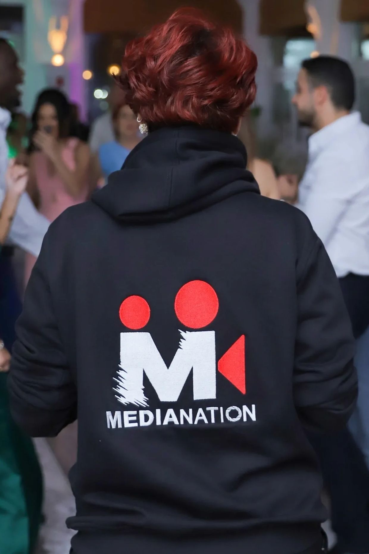 Person wearing a black hoodie with a MediaNation logo on the back.