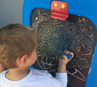 A kid drawing on a drawing board