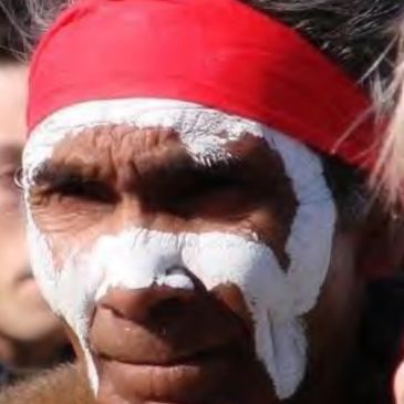 Man with white face paint and red headband.