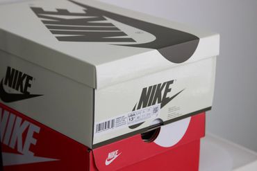 Two stacked Nike shoeboxes, one red and one white with black logo.