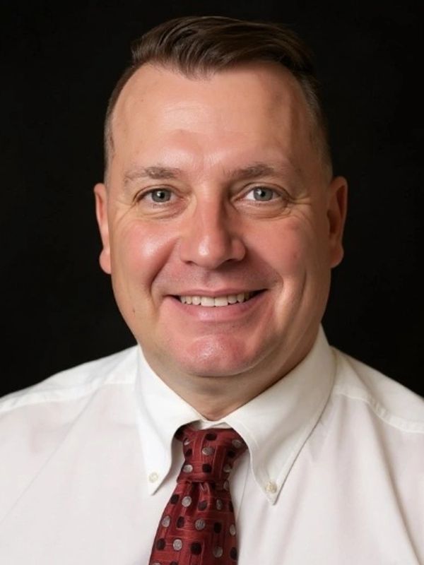 Smiling man in white shirt and red tie.