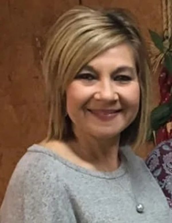 Woman smiling with blonde hair and gray sweater.