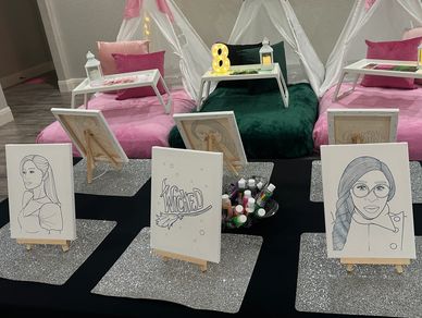 Art setup with portrait sketches and painting supplies on glittery mats.