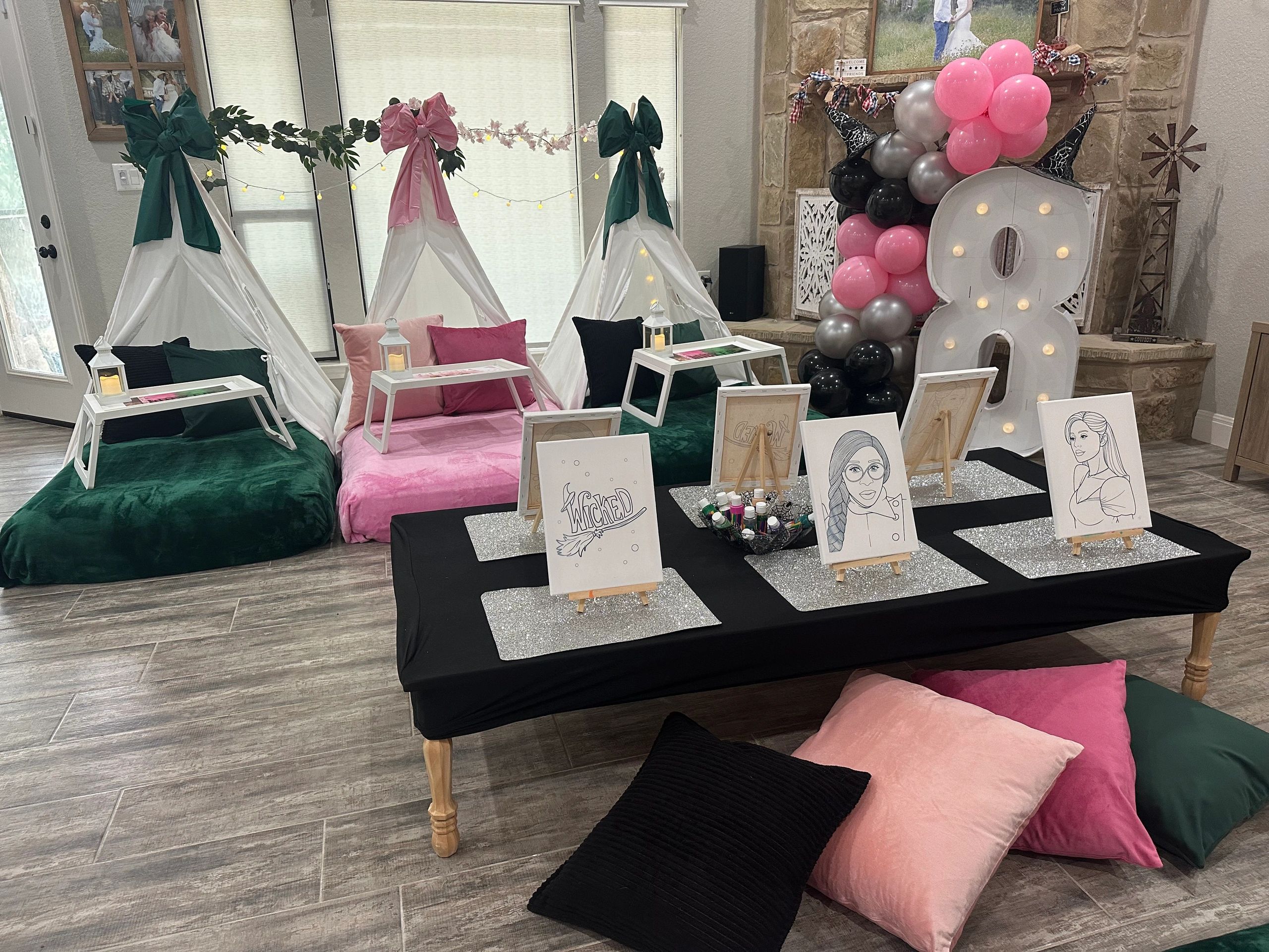 Cozy indoor teepee setup with art supplies, pillows, and festive balloons for a creative party.