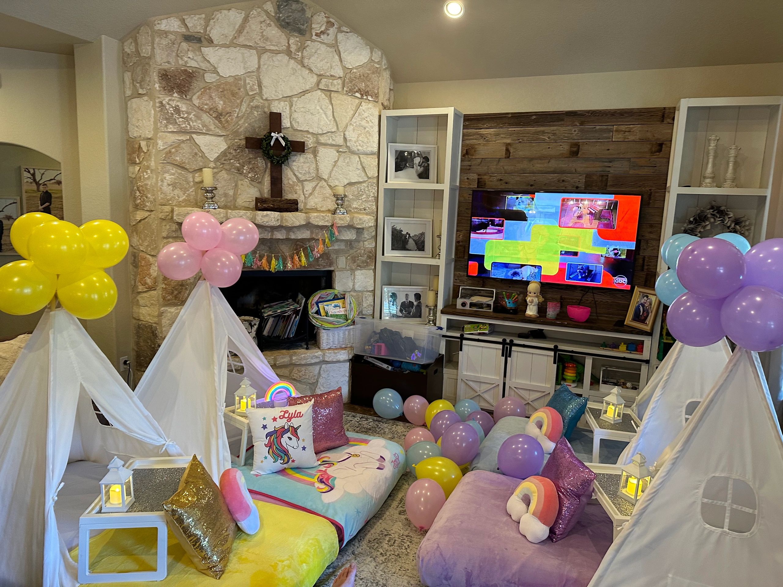 Children's unicorn-themed party setup with balloons and teepees in a cozy living room.