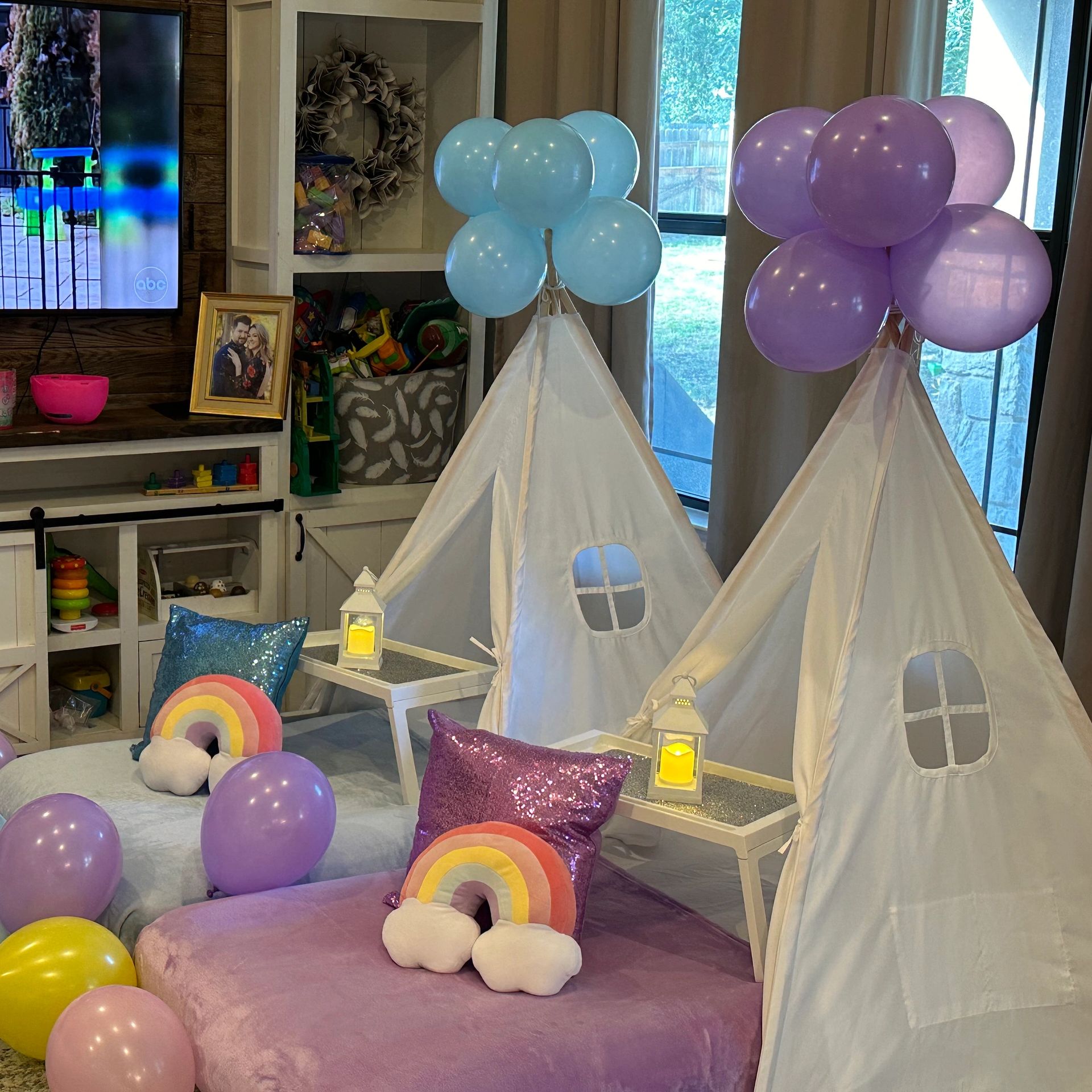 Indoor kids' play area with teepees, balloons, and colorful pillows.
