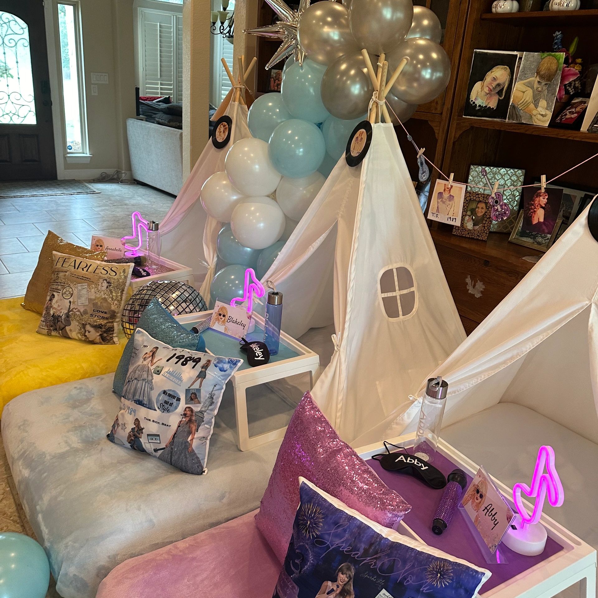 Children's teepee party setup with personalized trays, pillows, and balloons.