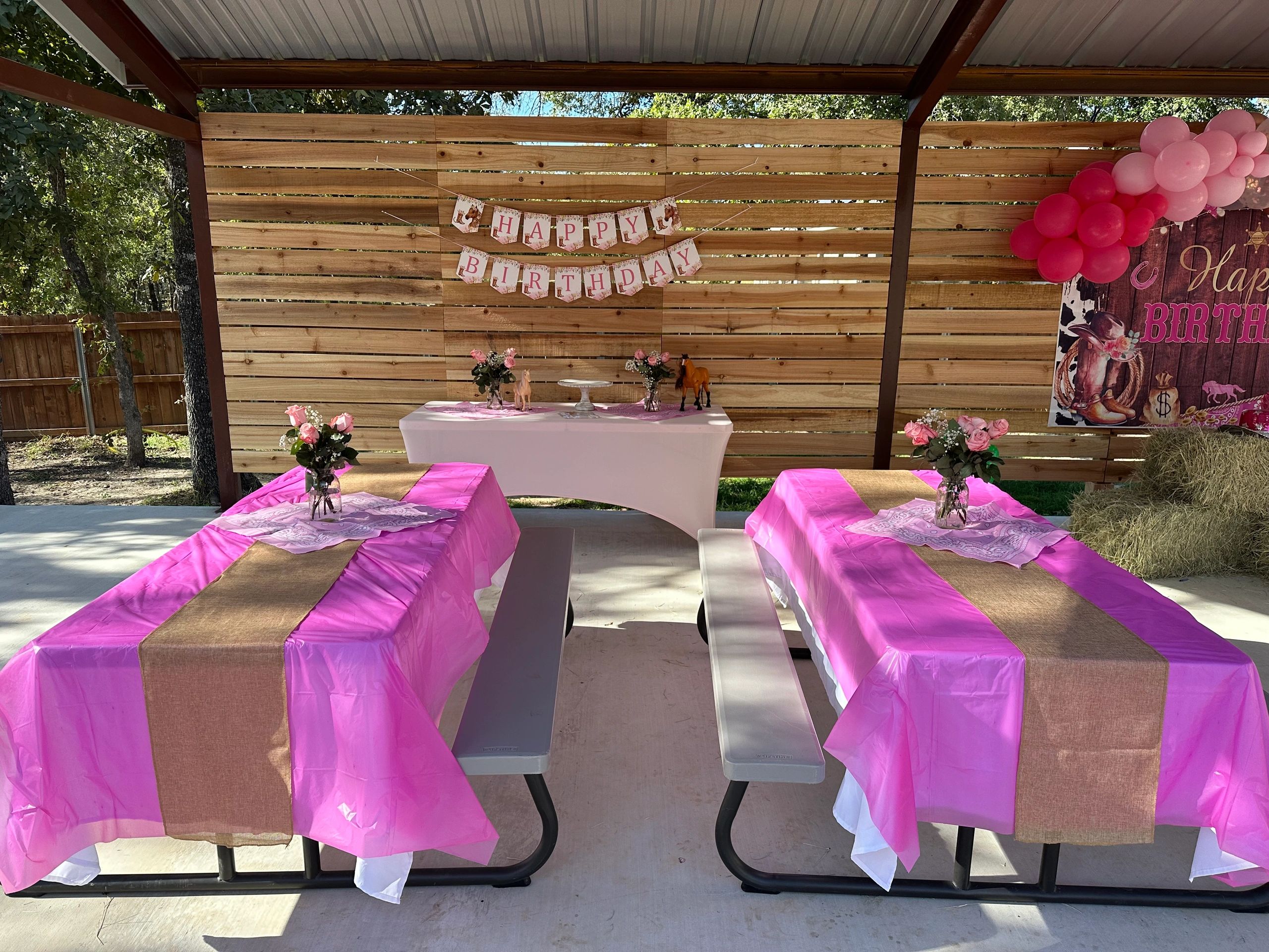 Outdoor pink-themed birthday party setup with floral decorations and balloons.