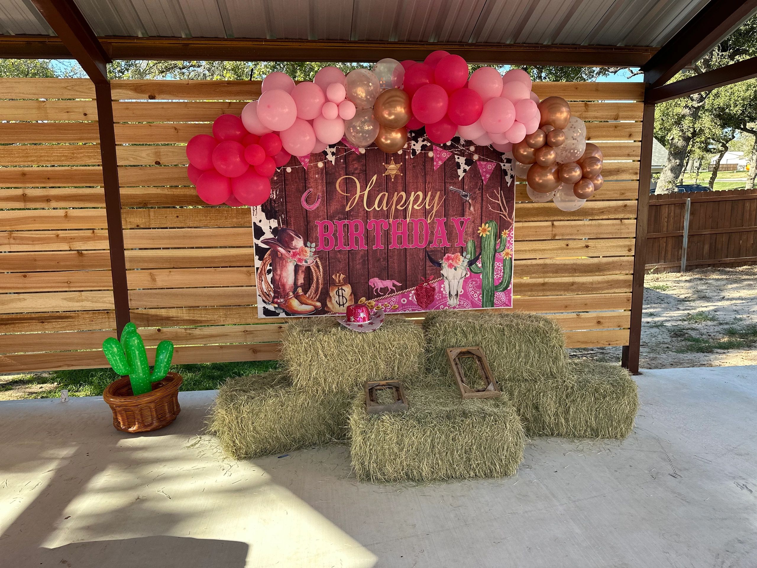 Western-themed birthday setup with balloons and hay bales.