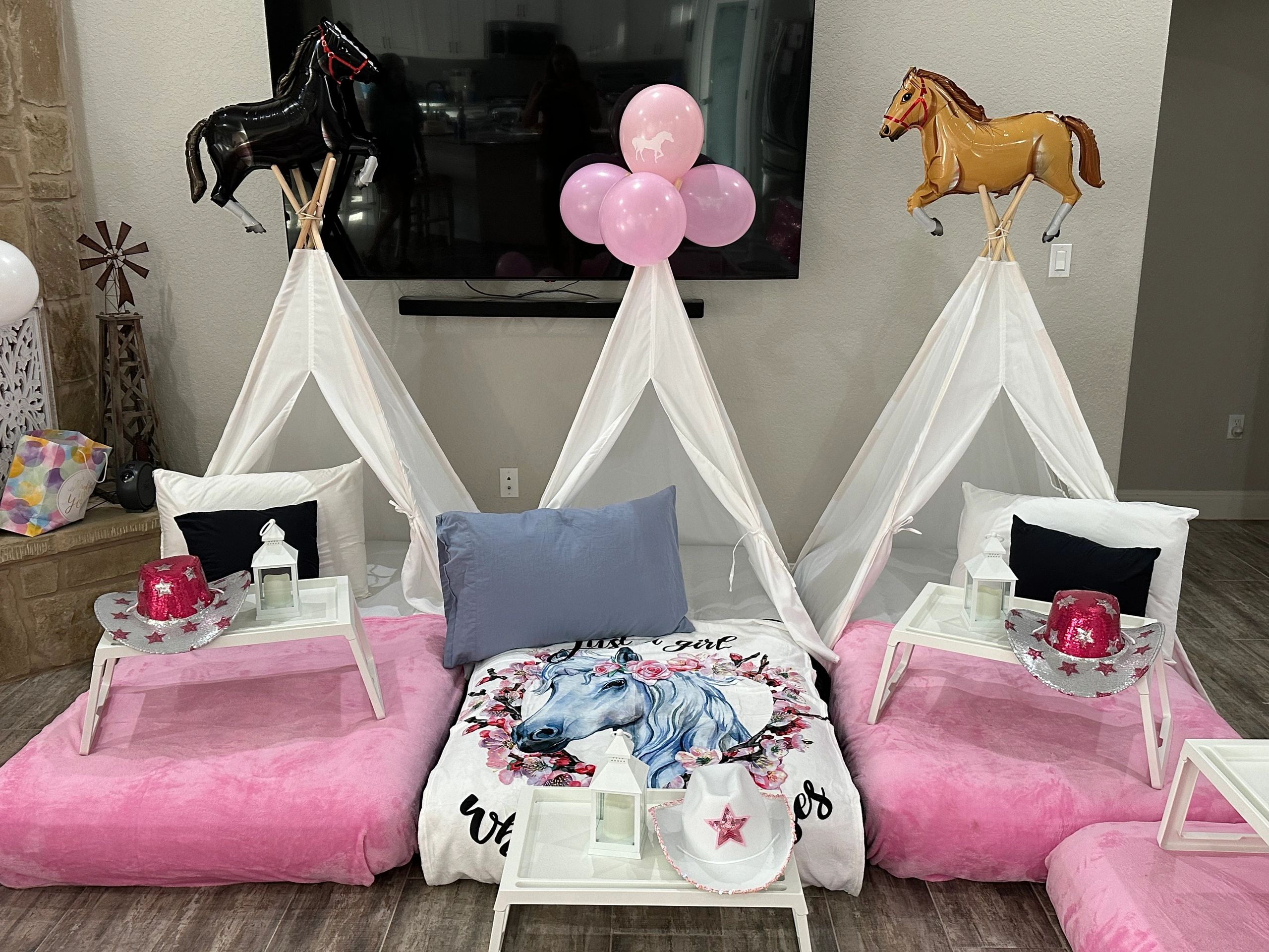 Cozy sleepover setup with teepees, horse balloons, and pink cowgirl hats.
