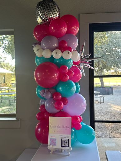 Colorful balloon tower with a disco ball and star decoration indoors.