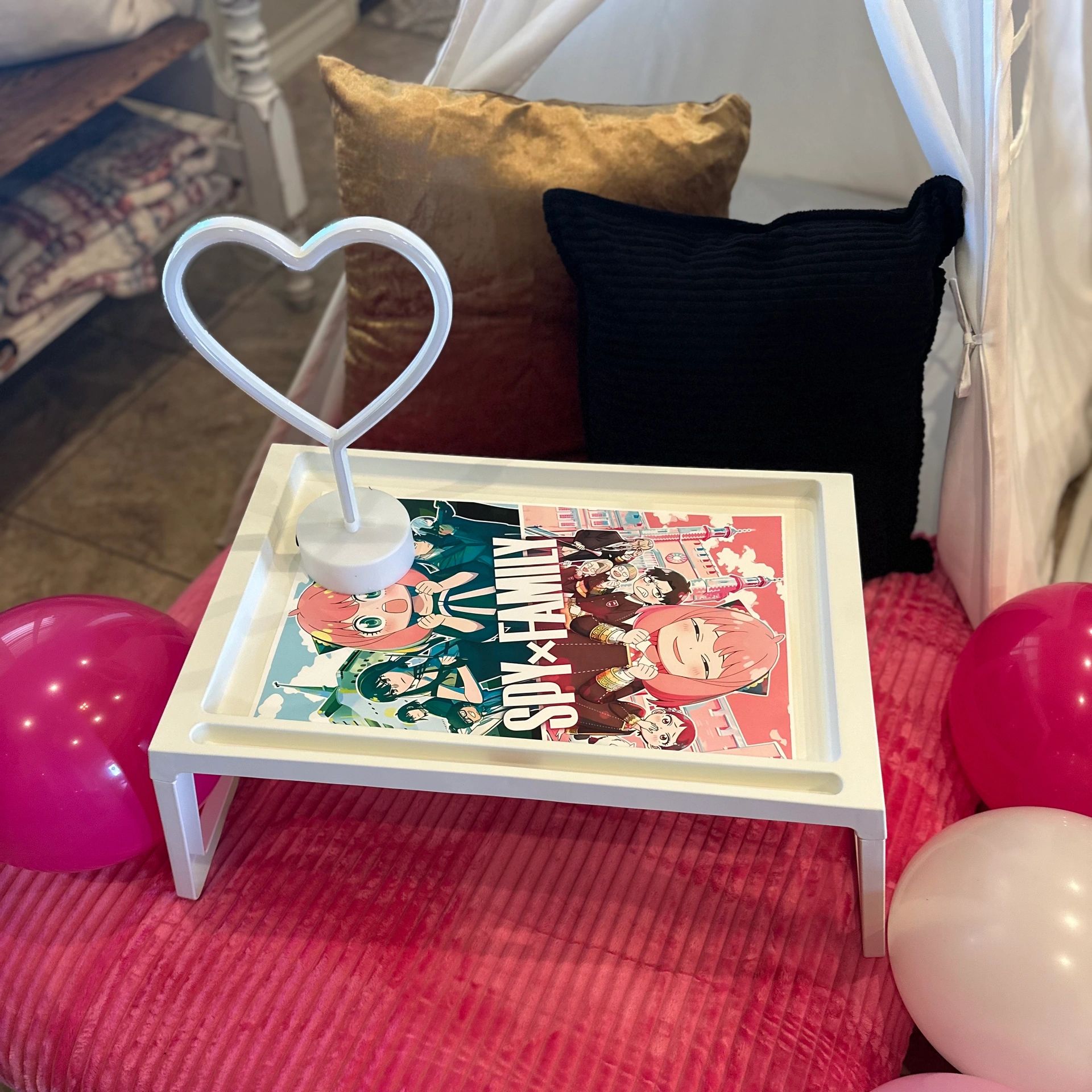 A cozy setup with pillows, heart-shaped light, and a Spy x Family manga on a white table.