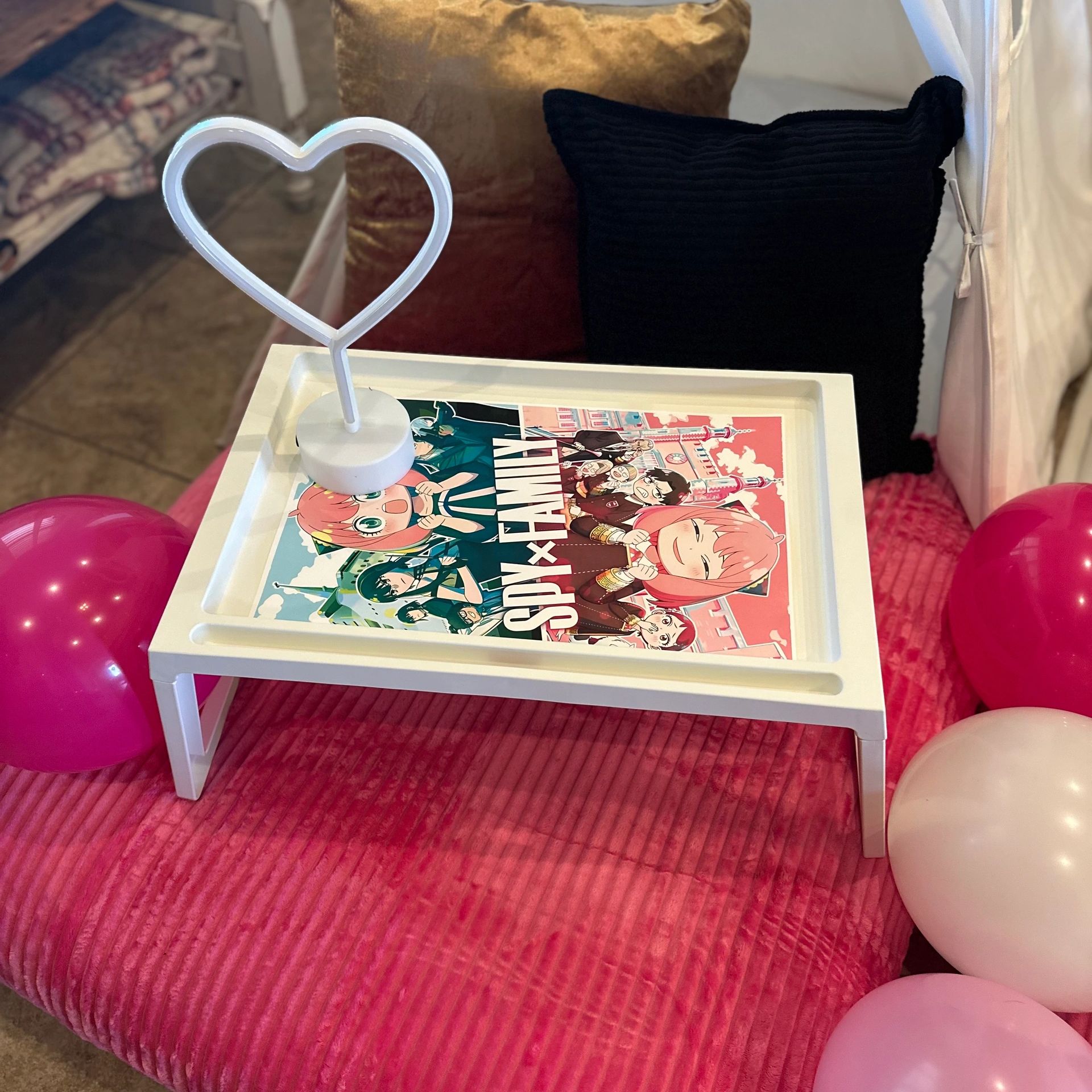 White tray on pink bed with heart-shaped light and manga comic book.